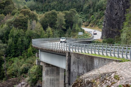 A beautiful shot of the bridge over the river surrounded by trees and mountainsの写真素材