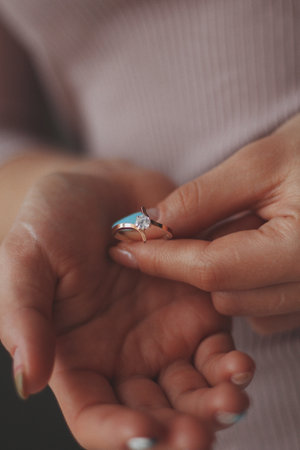 A vertical closeup shot of a female holding a beautiful gold diamond ringの写真素材