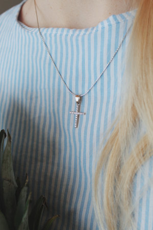 A closeup shot of a female in a blue shirt wearing a beautiful necklace with a nice pendant