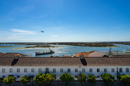 The tower bell of Faro Cathedral with a plane landing at Faro airport, Algarve, Portugalの写真素材