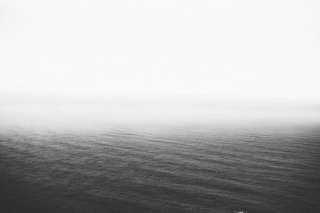 A greyscale shot of the calm ocean slowly disappearing at the horizon - perfect for backgroundの写真素材