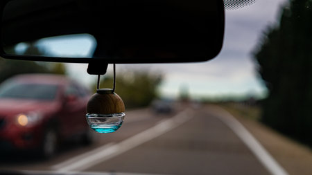A bottle of the car fragrance refresher hanging on the mirror