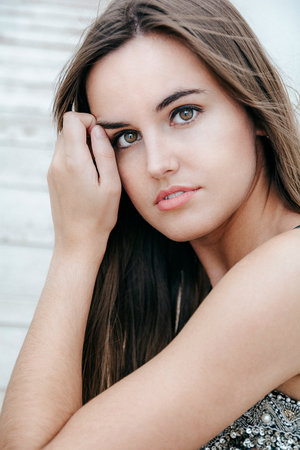 A closeup shot of an attractive brunette girl staring at the camera while sitting on the stairsの写真素材