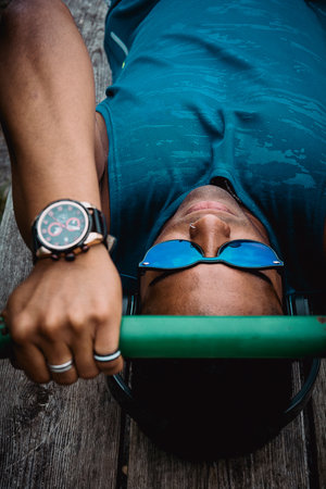 The young fit man with sunglasses and a blue shirt working out in the park while listening to musicの写真素材