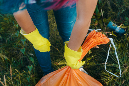 A young female collecting the trash and putting in a plastic garbage bag - environmental pollution...