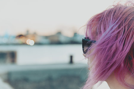 A closeup shot of a pretty pink-haired young female with a piercing and sunglassesの写真素材