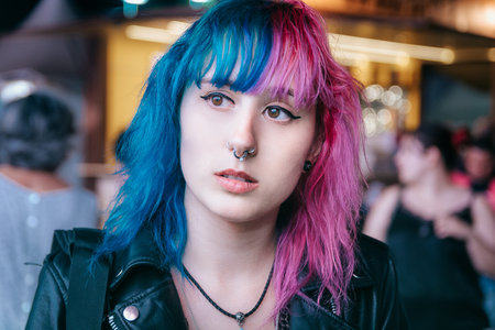 A portrait of a young female with pink and blue hair with a serious facial expressionの写真素材