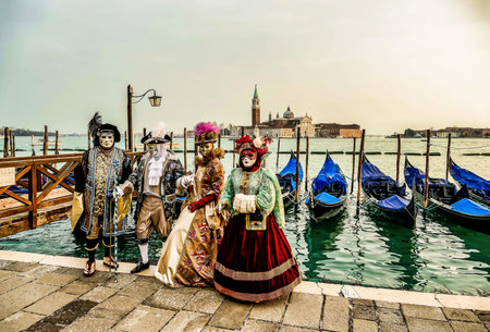 A group of people wearing costumes and masks standing by the water in Venice, Italyの写真素材