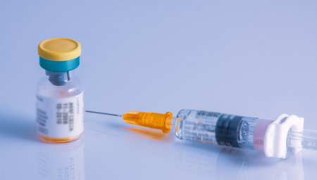 A closeup shot of a syringe a vial on a white glossy surface