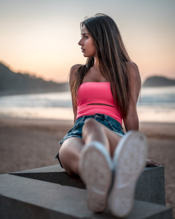 A vertical shot of an attractive female sitting on the beach by the ocean captured in Zarautz, Spainの写真素材