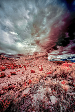 A vertical low angle shot of a desert surrounded by cliffs under the beautiful sky shot in infraredの写真素材