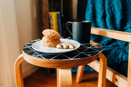 A plate of delicious cookies next to a black mug of coffee on a black table in a coffee houseの写真素材