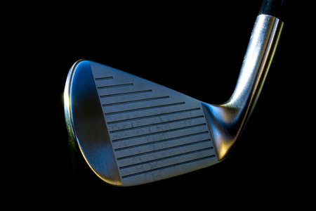 A closeup of a metal golf club against a black backgroundの写真素材