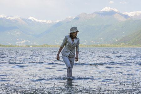 A woman walking in the lake with tall mountains in the backgroundの写真素材