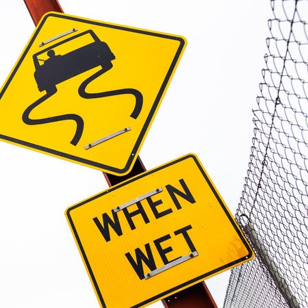 A closeup shot of a road wet sign on a metal poleの写真素材