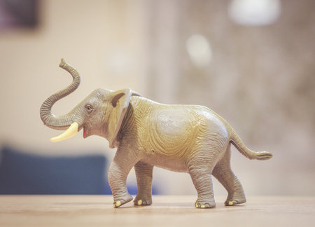 A closeup shot of a plastic toy elephant on a wooden surface with a blurred background