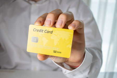 A person holding a yellow credit card with a blurred backgroundの写真素材