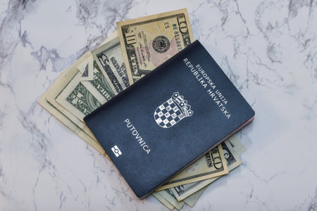 A high angle view of a Croatian Passport on dollars on the table under the lights - money conceptの写真素材