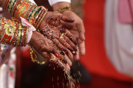 A closeup shot of a couple dropping grains on the floor under the lights during an Indian weddingの写真素材