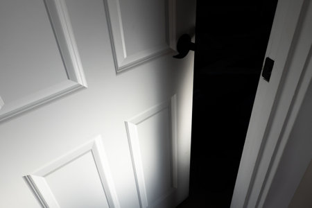 A high angle shot of a half-open door with a dark room insideの写真素材