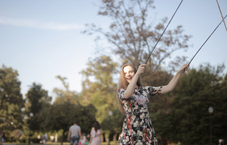 A beautiful picture of a smiling girl playing with sticks in the park against a blurry background