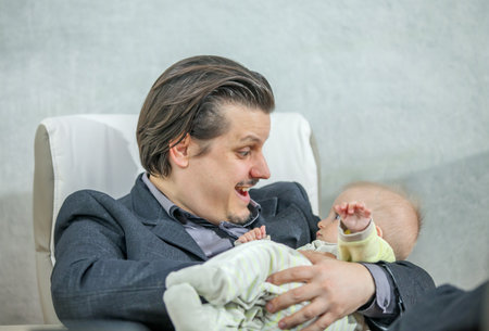 A young businessman holding a cute baby - the concept of happiness and family