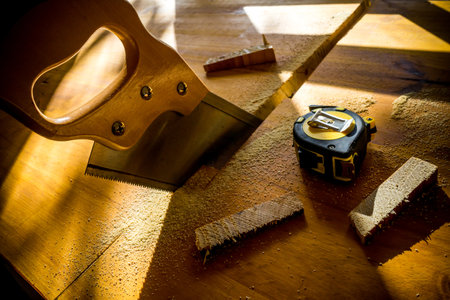 A high angle shot of a saw and a measuring tape on some pieces of woodの写真素材