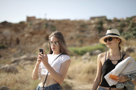 A beautiful shot of two females having a fun time with sunhats and glasses with a blurry backgroundの写真素材
