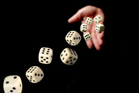 Hand throwing dice towards viewer isolated on black backgroundの写真素材