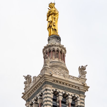 A vertical shot of the Virgin Mary statue on the bell tower of Notre dame de la Garde basilicaの写真素材