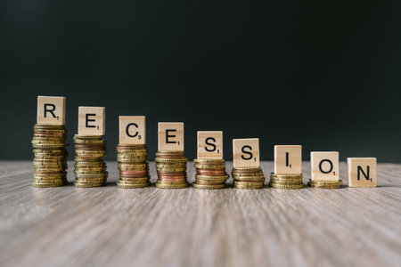 The word recession on decreasing coins. Concept for economic collapse and unemployment during a...