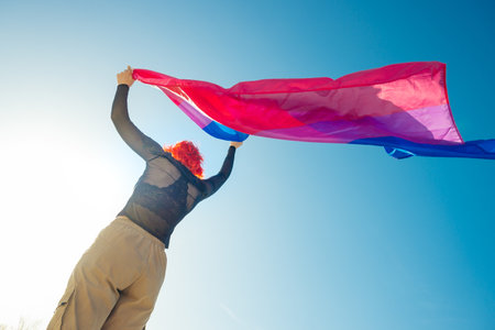 A beautiful low angle shot of a female waving red and blue flagの写真素材