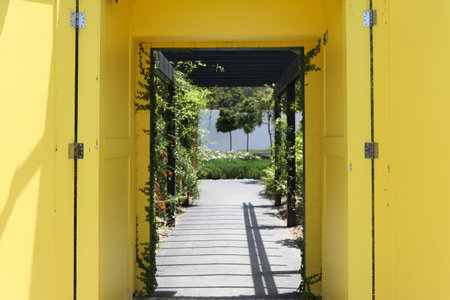 An amazing view od an outdoor yellow corridor going to a beautiful garden