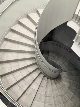 a vertical greyscale shot of round staircase with interesting modern architectureの写真素材