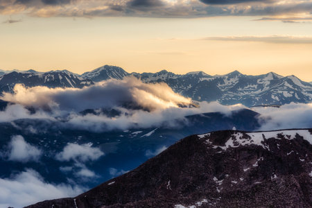 A beautiful sunset view with snow covered mountains and clouds as viewed from Mount Evans in...