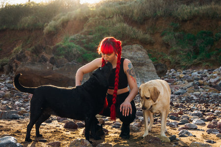 An amazing shot of a young red-haired female playing with her dogs