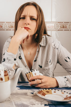 A vertical shot of a woman with a nose piercing and angry face drinking coffeeの写真素材