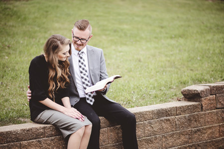A couple sitting in a garden and lovingly reading a book togetherの写真素材