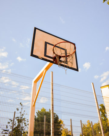 A low angle shot of a basketball ring with chain net against a blue cloudy sky