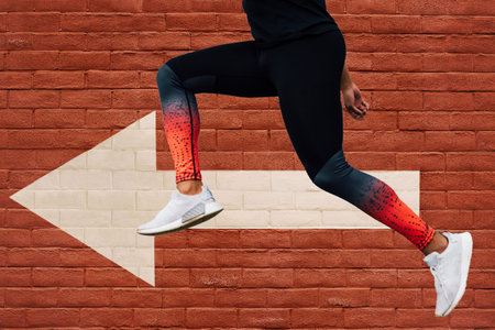 A young man running and working out with a brick wall and an arrow on the background