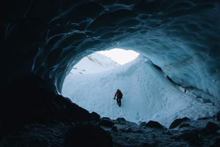 A silhouette of an adventurous young man hiking in a cave in winterの写真素材