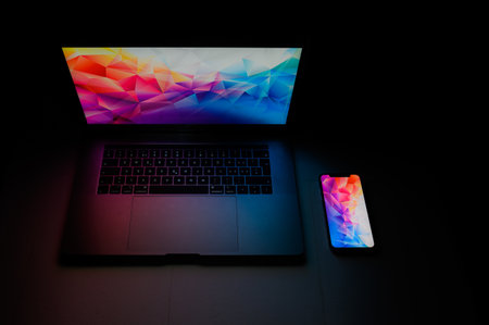 Open laptop with digital tablet and white smartphone. All with isolated screen on modern LED desk....