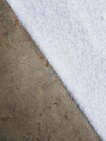 A vertical high angle shot of a concrete ground half-covered with snowの写真素材