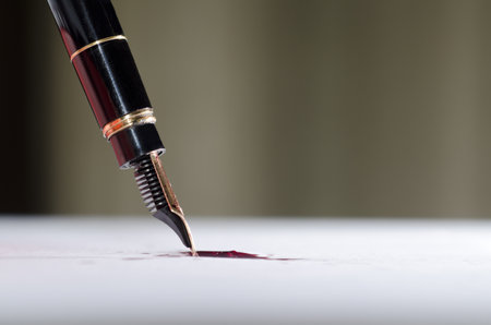 A selective focus shot of stylograph pen with red ink on white paper