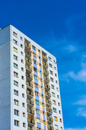 A vertical shot of a tall modern architectural building with a blue sky in the background