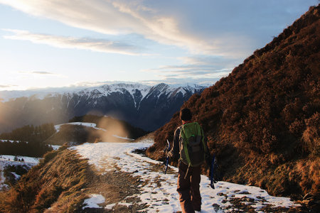 A behind shot of the hiker in the mountains covered in snow