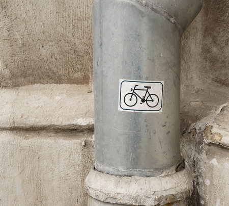 A vertical shot of a white bicycle symbol sticker on a downspout pipeの写真素材