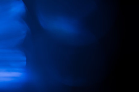 A dark wallpaper with bokeh light leaks against a black background for overlaysの写真素材