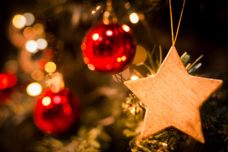 A soft focus of a wooden star ornament hanging from a Christmas tree with blurry backgroundの写真素材