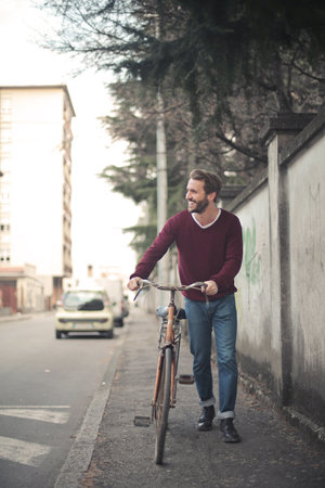 A vertical shot of a young male riding a bicycle on the sidewalkの写真素材